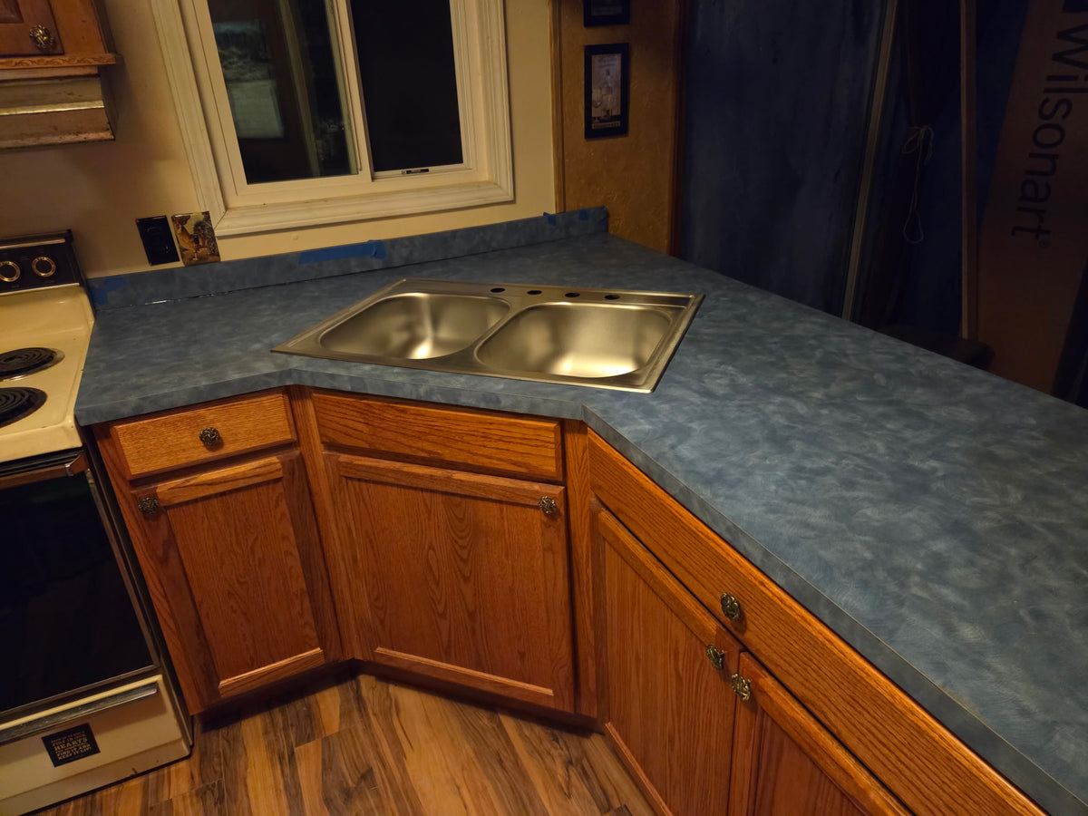 Blue slate laminate countertop with mitered corner seam and stainless steel double bowl drop-in sink